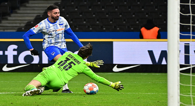 Hertha's Algerian forward Ishak Belfodil (Back) scores the equalising goal 1:1 against Dortmund's Swiss goalkeeper Marwin Hitz during the German first division Bundesliga football match Hertha Berlin vs Borussia Dortmund in Berlin on December 18, 2021. - DFL REGULATIONS PROHIBIT ANY USE OF PHOTOGRAPHS AS IMAGE SEQUENCES AND/OR QUASI-VIDEO (Photo by Tobias SCHWARZ / AFP) / DFL REGULATIONS PROHIBIT ANY USE OF PHOTOGRAPHS AS IMAGE SEQUENCES AND/OR QUASI-VIDEO (Photo by TOBIAS SCHWARZ/AFP via Getty Images)